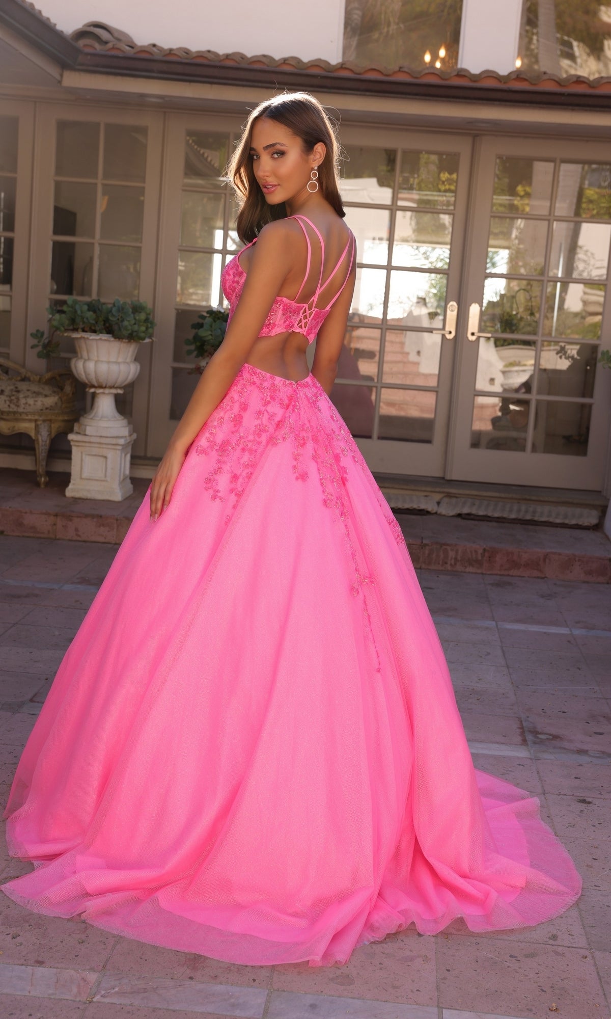 A woman wearing the Long Corset Glitter Prom Ball Gown H1357 stands on a stone patio in front of a house.